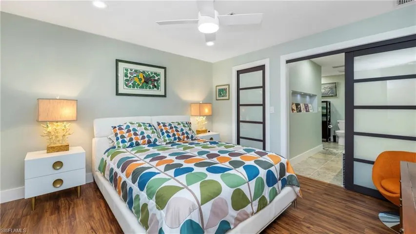 Bedroom featuring a ceiling fan, dark wood-style floors, and ensuite bath