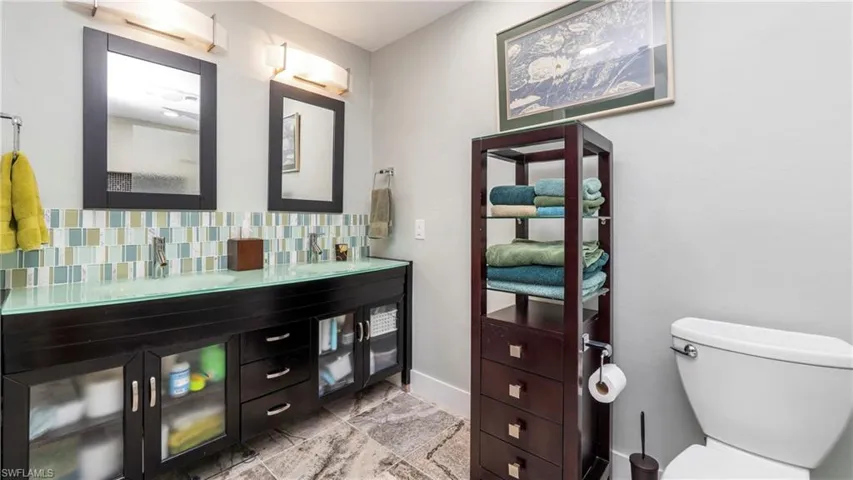 Full bathroom with double vanity and decorative backsplash