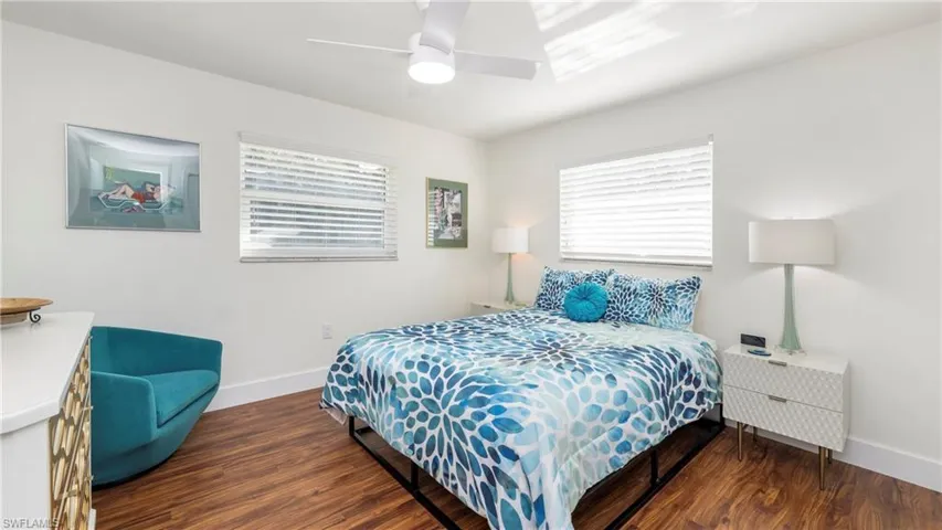 Bedroom featuring dark wood-style floors, ceiling fan, and multiple windows
