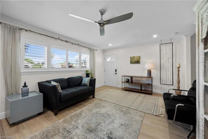 Living room with ceiling fan, crown molding, and wood-type flooring
