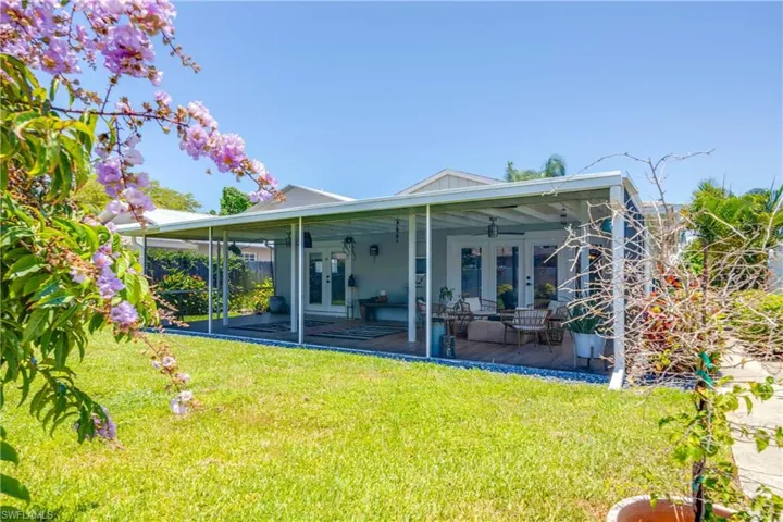 Rear view of property featuring a yard, ceiling fan, french doors, and a patio area