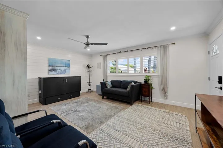 Living room with ornamental molding, ceiling fan, and light hardwood / wood-style flooring