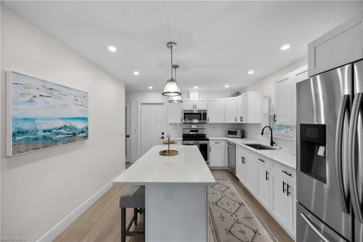 Kitchen with a center island, white cabinetry, stainless steel appliances, backsplash, and sink