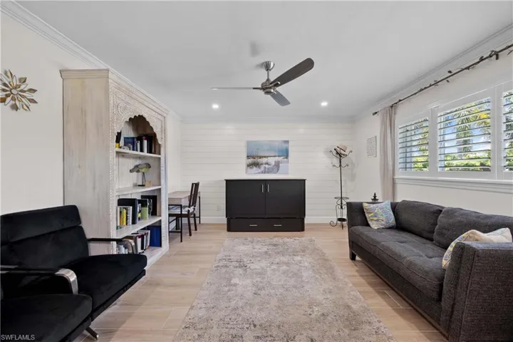 Living room with crown molding, built in features, ceiling fan, and light hardwood / wood-style flooring