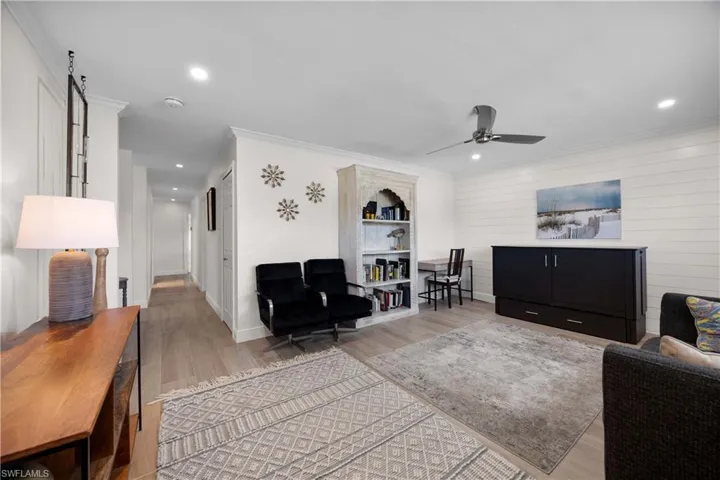Living room featuring ceiling fan, a barn door, hardwood / wood-style flooring, and crown molding