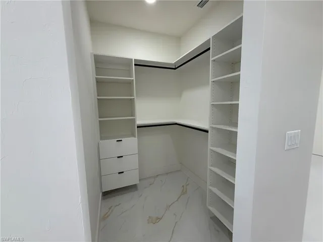 Spacious closet featuring light marble finish floors