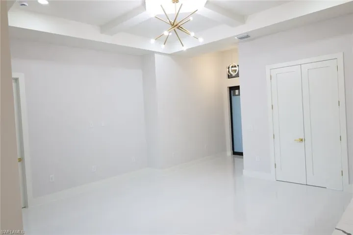 Unfurnished room featuring beamed ceiling and a chandelier