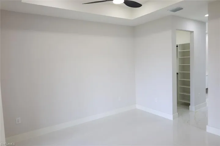 Unfurnished room with ceiling fan, light tile patterned floors, and a raised ceiling
