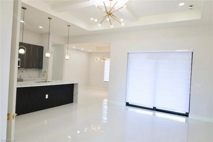 Kitchen featuring hanging lights, light stone counters, modern cabinets, a tray ceiling, and beamed ceiling