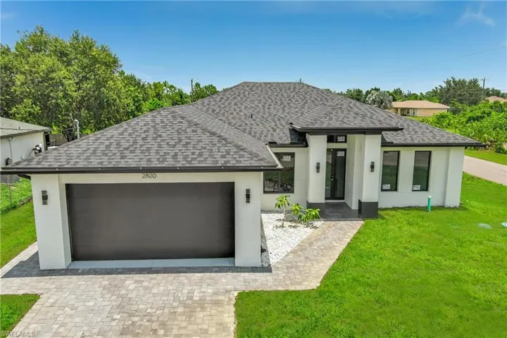 View of front facade with a front lawn, stucco siding, and decorative driveway