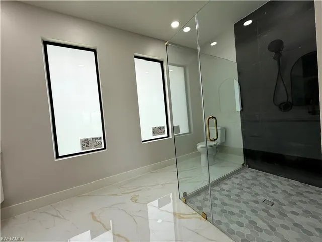 Bathroom featuring recessed lighting, light marble finish floors, and a stall shower