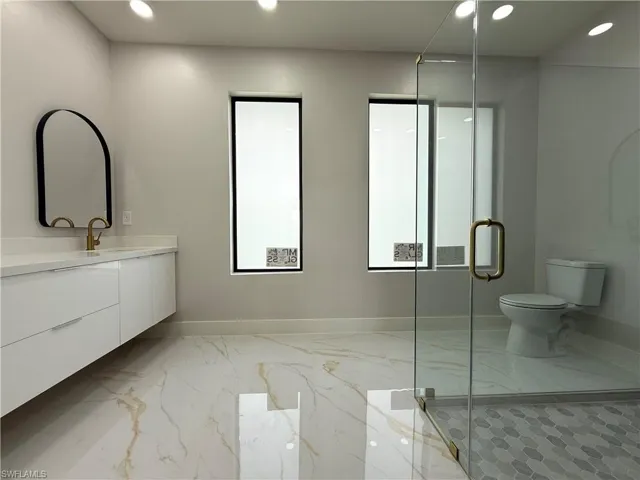 Bathroom with recessed lighting, vanity, light marble finish floors, and a shower stall