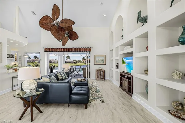 Vaulted ceilings, custom wall-to-wall built-in shelving, LVP flooring, and multi-blade ceiling fan