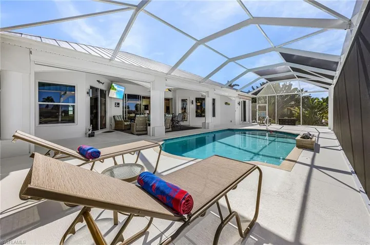 Screened-in outdoor living area featuring a swimming pool, concrete pool deck, and covered lanai