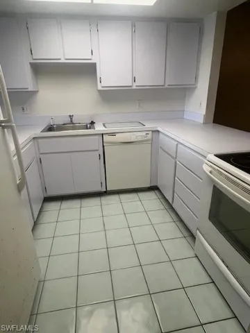 Kitchen with range, light tile patterned floors, light countertops, and white dishwasher