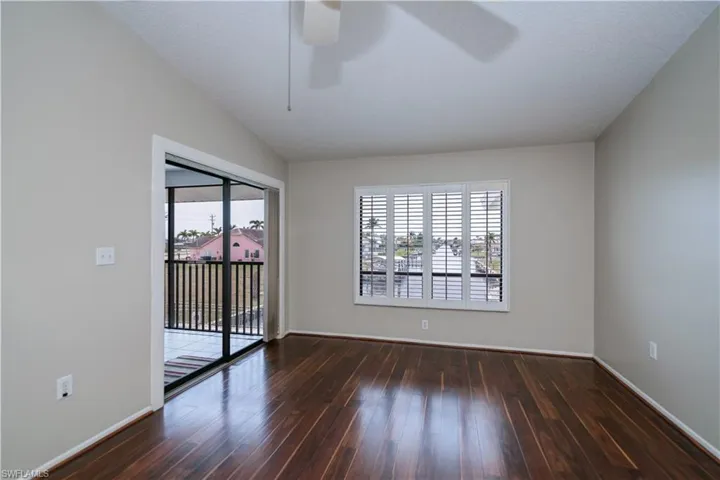 Spare room featuring healthy amount of natural light, dark wood-type flooring, and ceiling fan