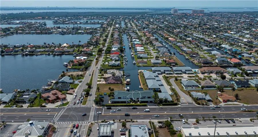 Aerial view of property and surrounding area featuring a nearby body of water and nearby suburban area