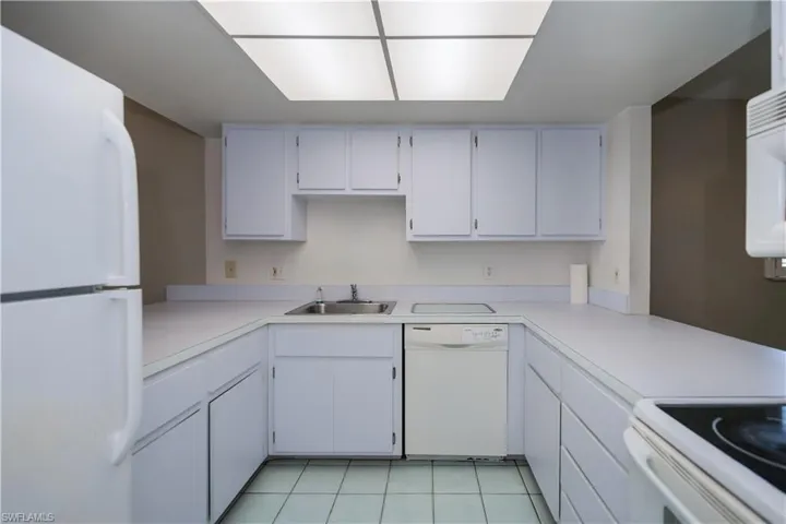 Kitchen with white appliances, white cabinets, light countertops, and light tile patterned floors