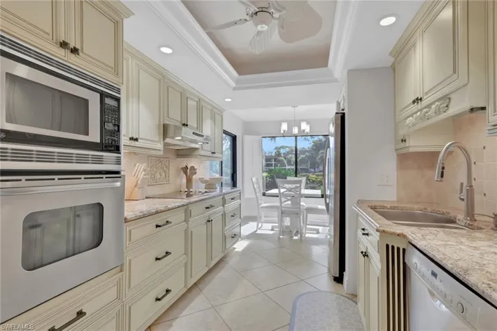 Kitchen with cream cabinets, stainless steel appliances, backsplash, recessed lighting, and light stone countertops