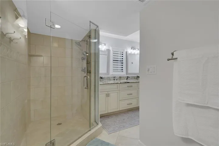Bathroom featuring vanity, a stall shower, light tile patterned flooring, and recessed lighting