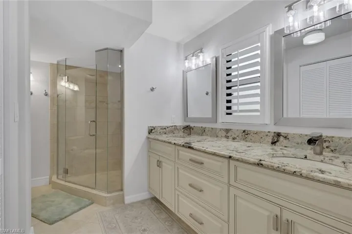 Bathroom featuring double vanity, a stall shower, and light tile patterned floors