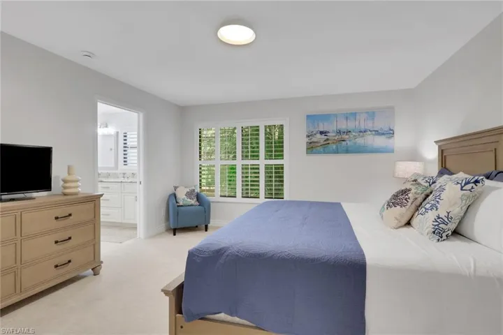 Carpeted bedroom with ensuite bathroom and baseboards
