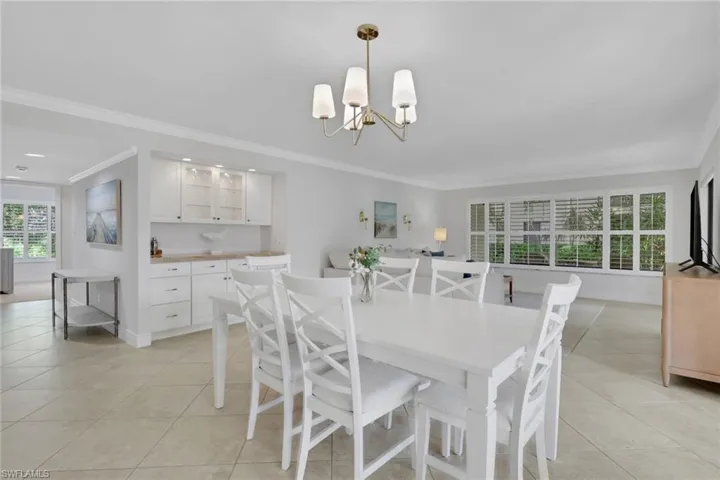 Dining space with ornamental molding, light tile patterned floors, and a chandelier