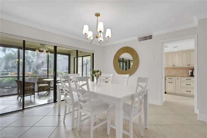 Dining space with light tile patterned floors, ornamental molding, and a chandelier