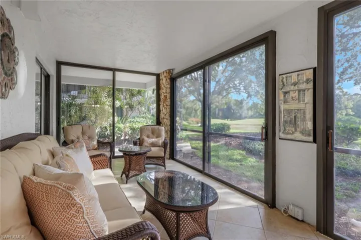 Sunroom featuring expansive windows, healthy amount of natural light, tile patterned flooring, and a textured wall
