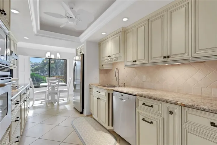 Kitchen with cream cabinetry, appliances with stainless steel finishes, decorative light fixtures, light stone countertops, and recessed lighting