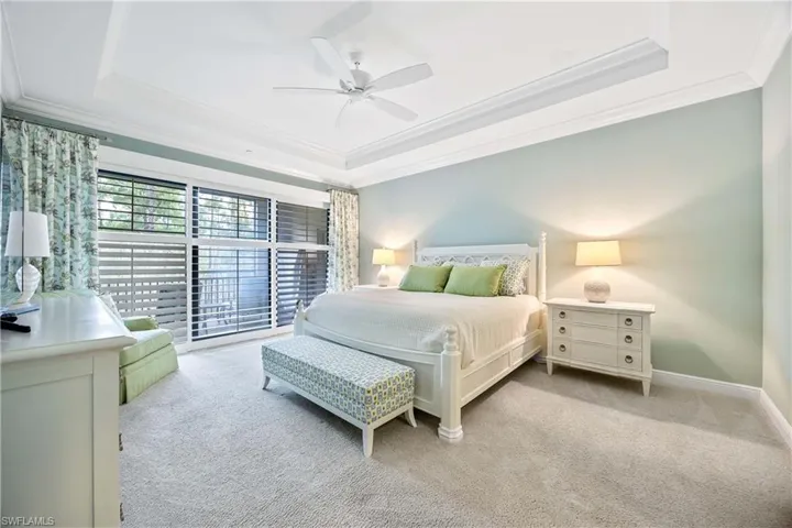Carpeted bedroom with a tray ceiling, crown molding, and ceiling fan