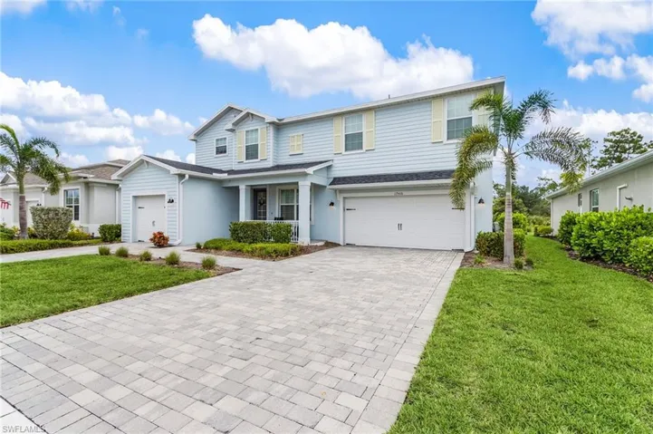Traditional-style house featuring a front yard, decorative driveway, and an attached garage