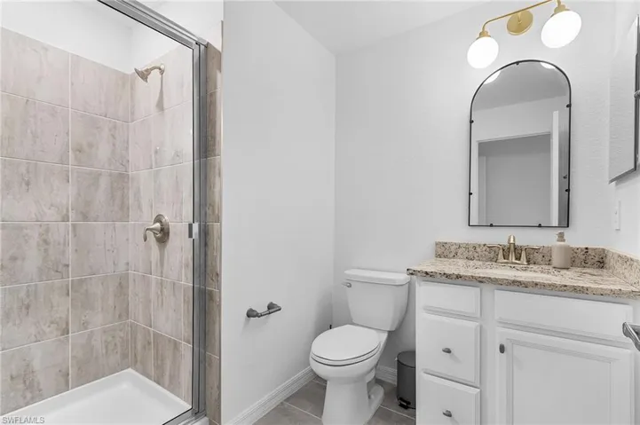 Full bath with vanity, a stall shower, and tile patterned floors