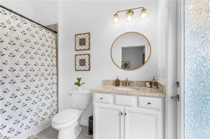 Bathroom with vanity, tile patterned floors, and a shower with shower curtain