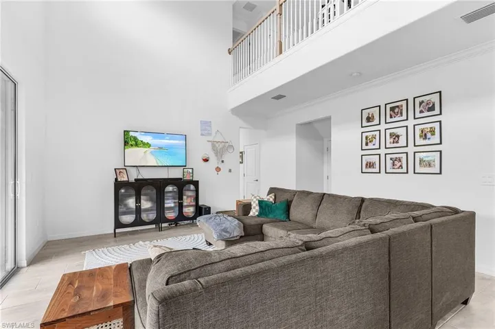 Living room with a towering ceiling, light wood-style floors, and crown molding