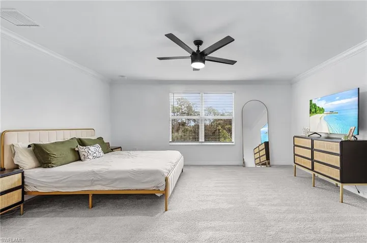 Carpeted bedroom featuring crown molding and ceiling fan