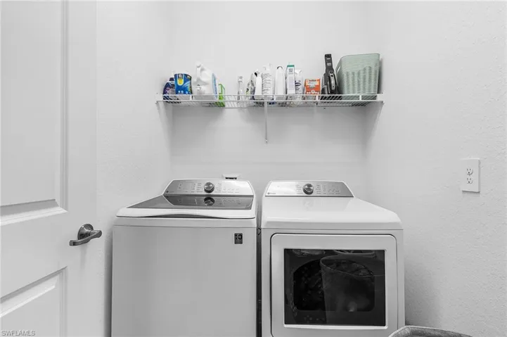 Washroom featuring independent washer and dryer and a textured wall