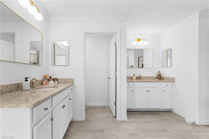 Bathroom with ornamental molding and two vanities