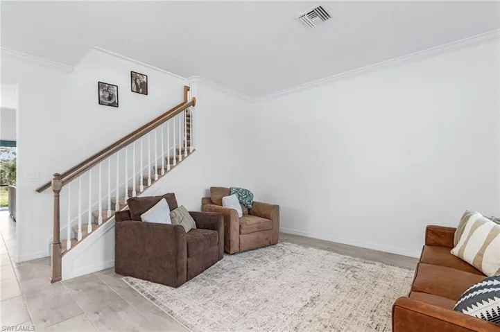 Living room featuring crown molding, light wood-style floors, and stairway