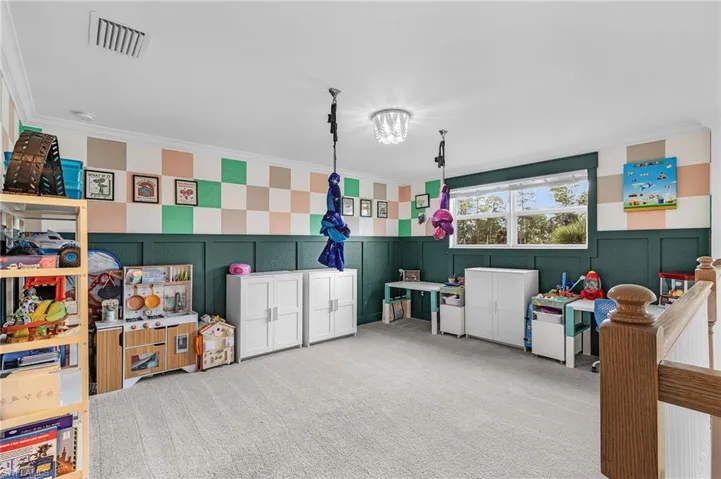 Game room with carpet, crown molding, and a decorative wall
