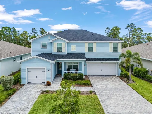 Traditional-style house with a shingled roof, covered porch, decorative driveway, and an attached garage