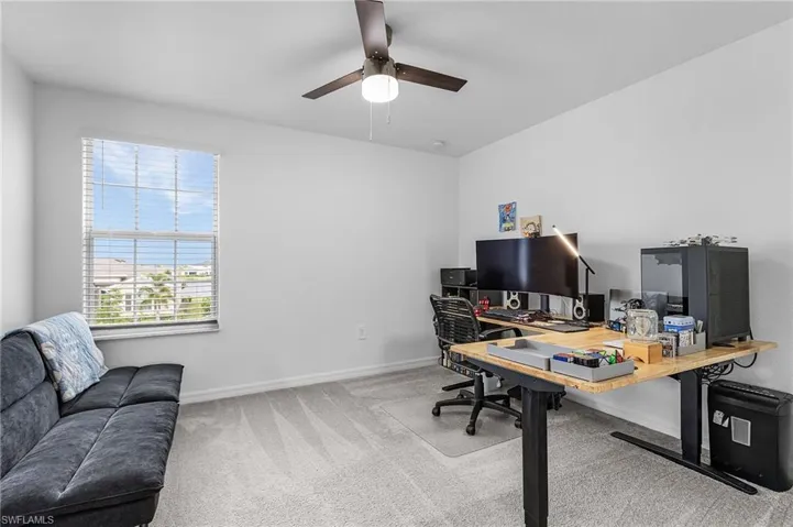 Carpeted home office featuring baseboards and ceiling fan