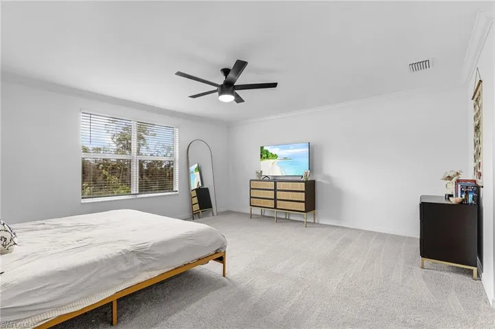 Bedroom with crown molding, carpet, and a ceiling fan