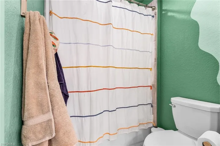 Full bath featuring a textured wall and toilet