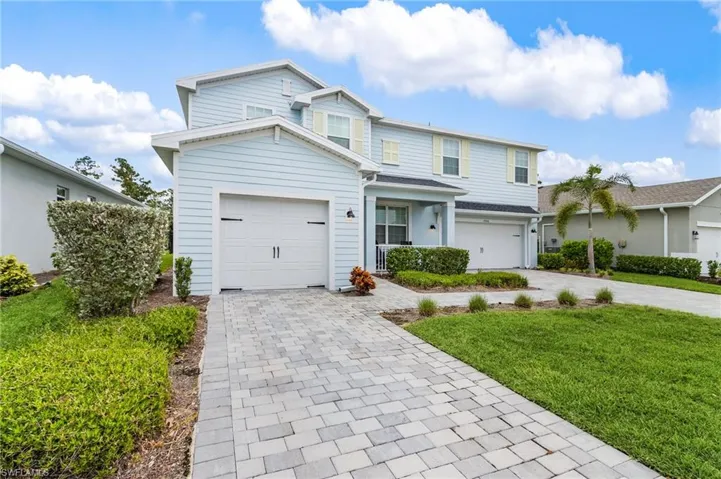 Traditional-style home with decorative driveway, a garage, and a front lawn