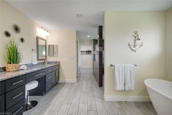 Spacious bathroom featuring an elongated double vanity with dark cabinetry and a light-toned countertop