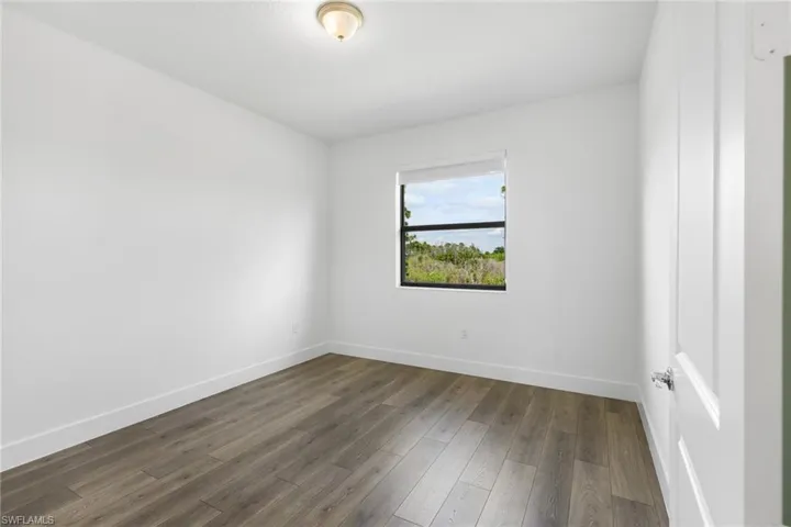Empty room with dark wood-style flooring and baseboards