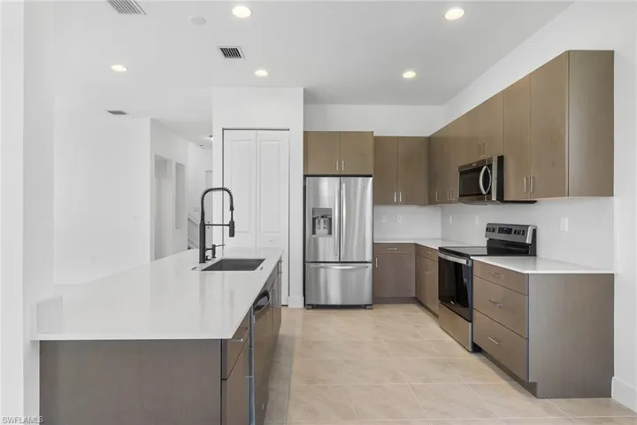 Kitchen featuring stainless steel appliances, light tile patterned flooring, recessed lighting, light stone countertops, and modern cabinets