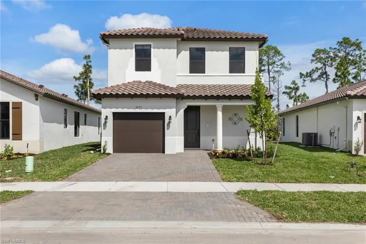 Mediterranean / spanish-style home featuring stucco siding, decorative driveway, a front yard, a tiled roof, and an attached garage
