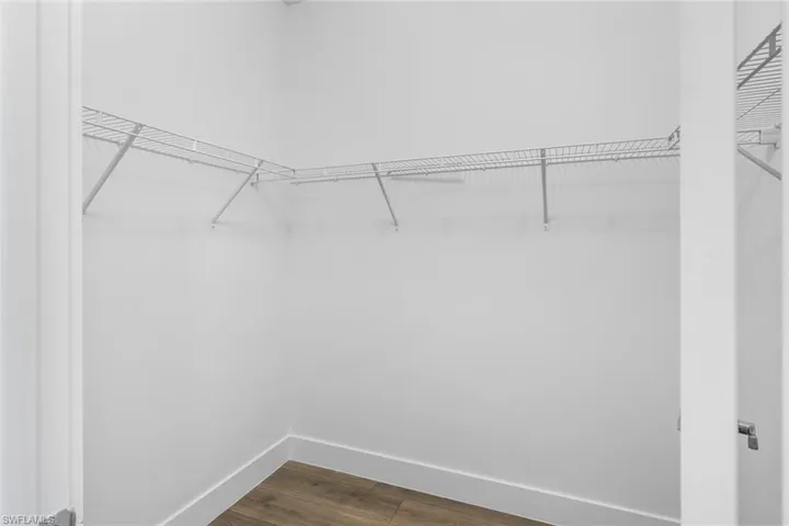 Walk in closet with dark wood finished floors